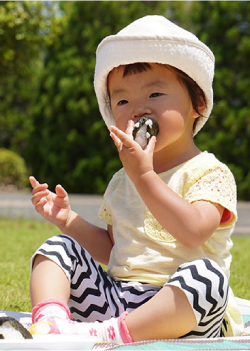 赤ちゃんがおにぎりを食べる写真